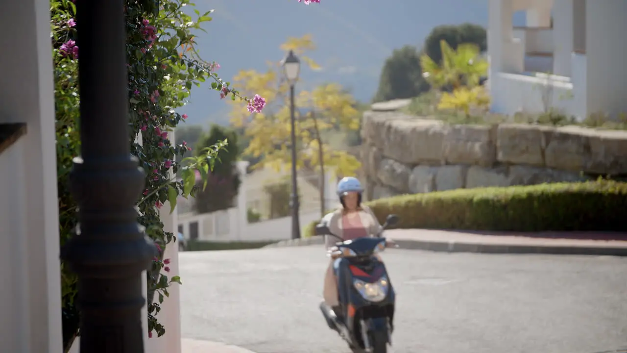 Young woman passing by on her scooter in a gated community