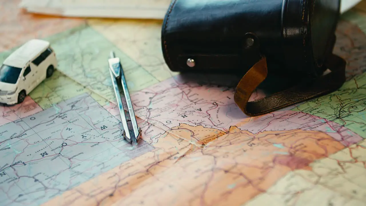 The camera slowly panning across the table on which is a binocular case a small car toy a map of America and a vintage camera