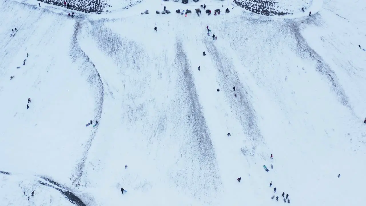 Local people sledding down snowy hill during winter in Iceland aerial