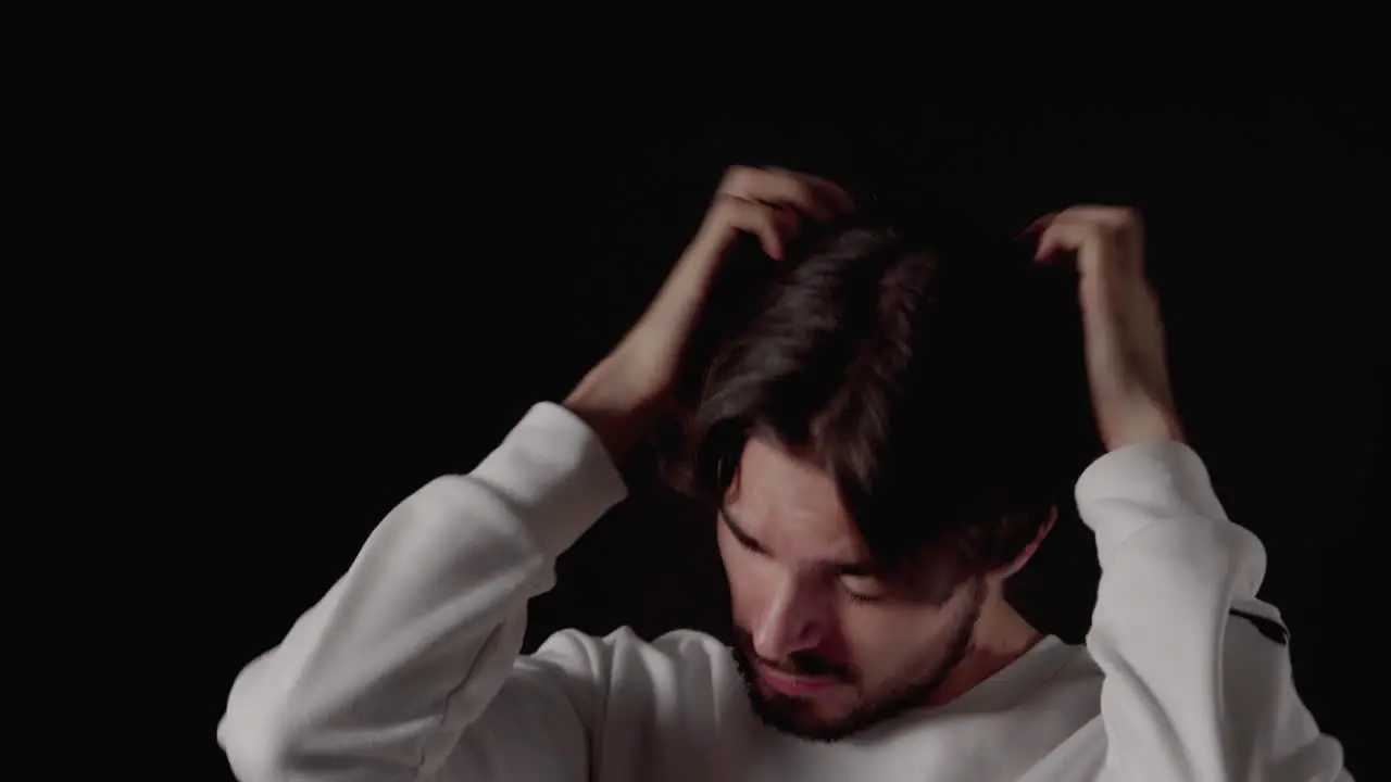 Trendy Young Man playing with andstraightening hair close black background