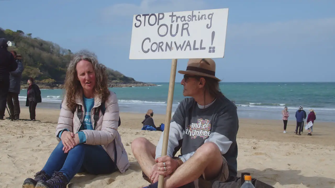 Two Local protesters a male and female sit on the beach of Carbis Bay Hotel St Ives Cornwall