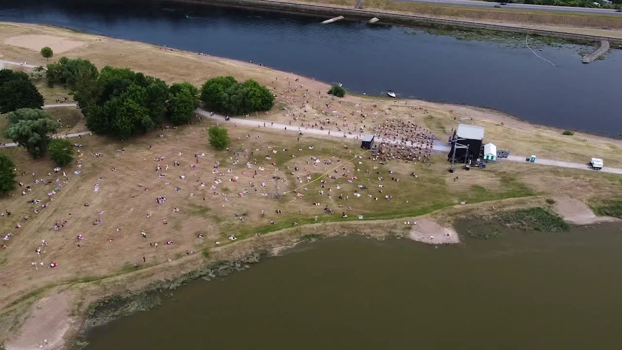 Music festival in two river conjunction with crowd of people aerial drone view