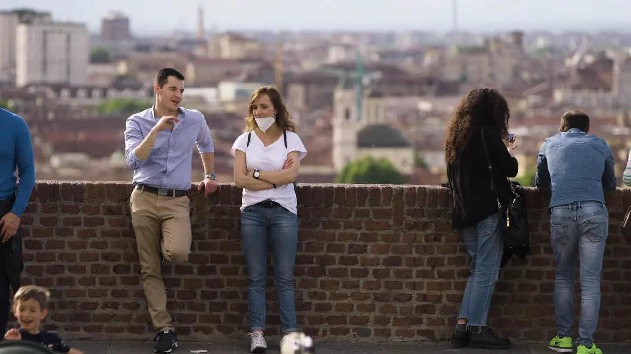 Tourists chilling by brick wall with city Turin Italy in background