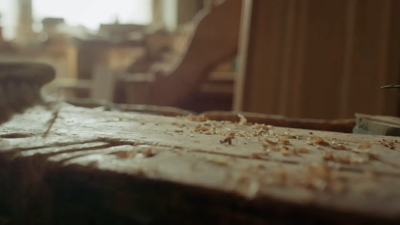 Man exempting from sawdust indoors Handyman cleaning wooden surface in studio