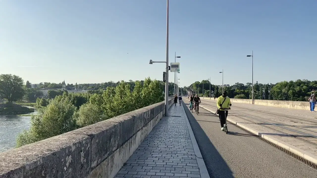 Cyclists and e scooter in slow motion passing over bridge Wilson in Tours France