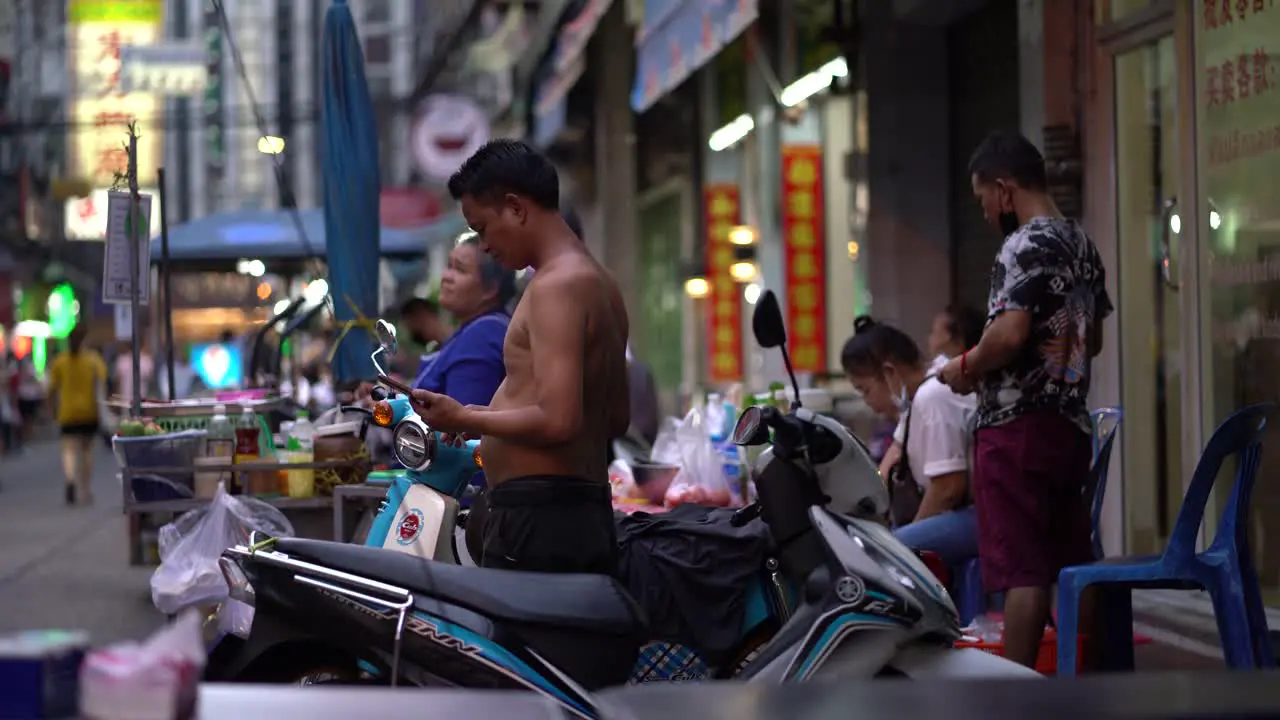 Shirtless man talking on the phone in Chinatown Bangkok