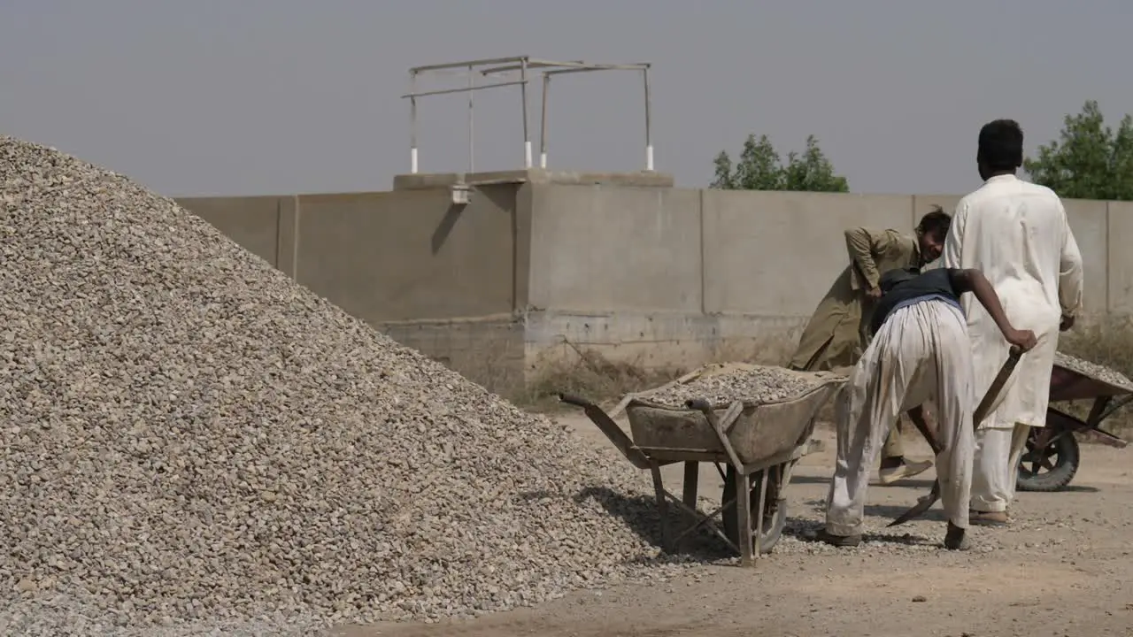 Manual Labourer Using Shovel To Fill Aggregate In Wheelbarrow In Karachi Pakistan