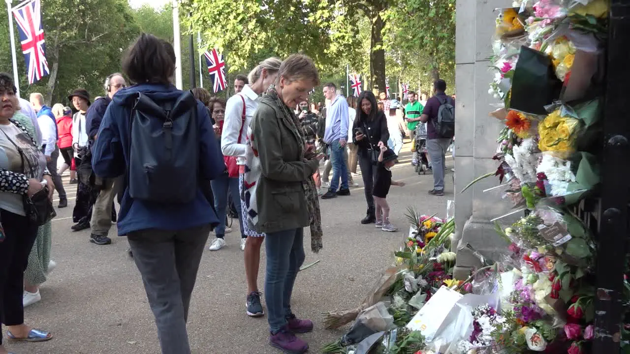 People leave flowers at a memorial to the Queen at the entrance to St James Park in London UK