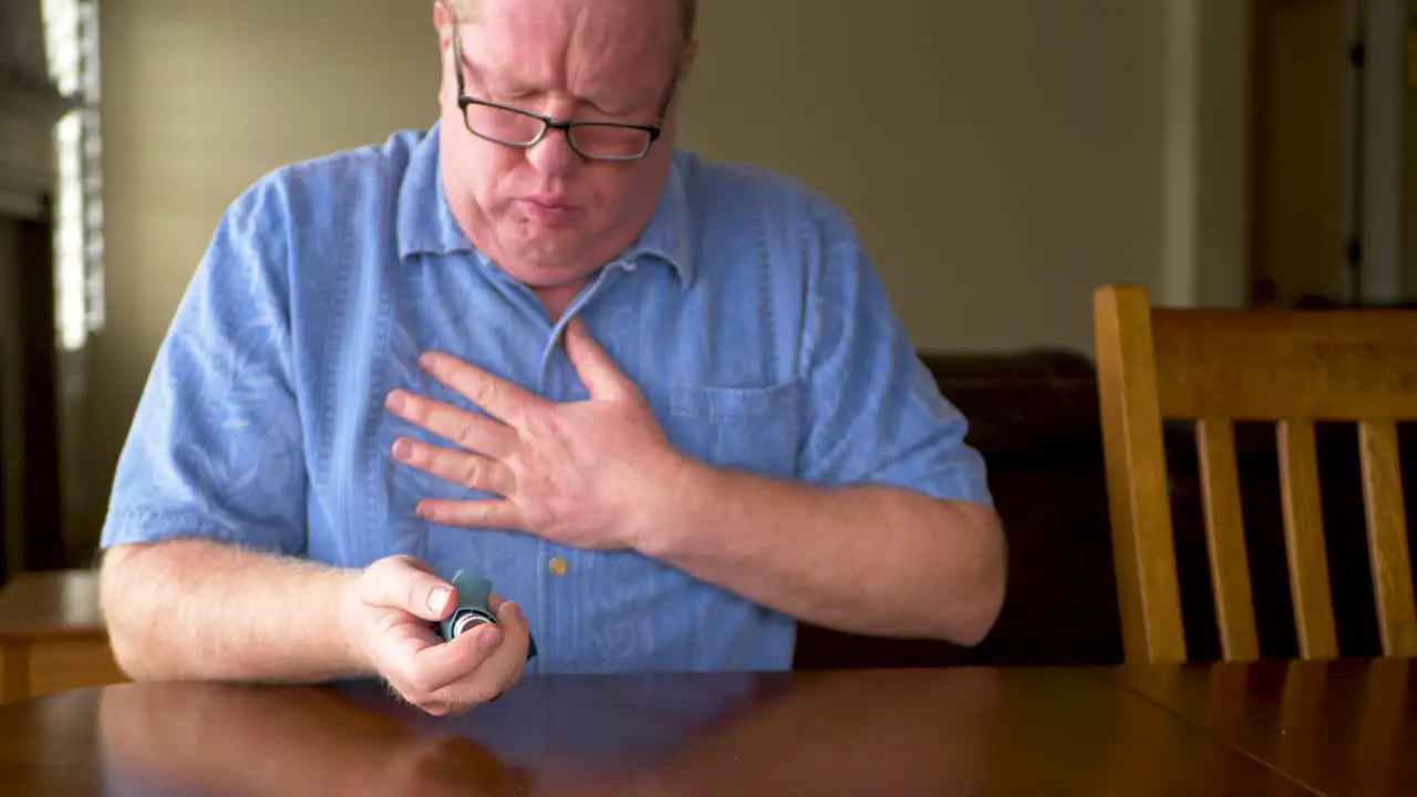 A mature man coughing and using an inhaler to clear lungs static shot