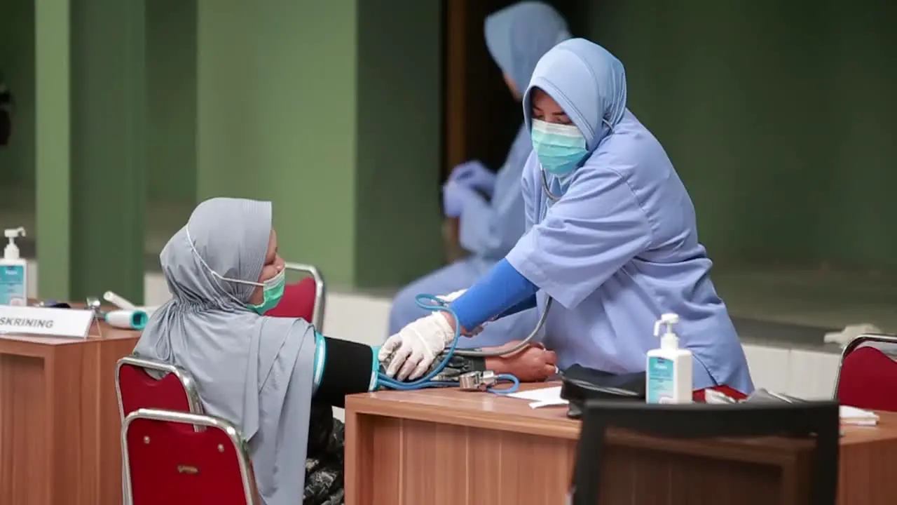 Doctor using sphygmomanometer with stethoscope checking blood pressure to a patient in the hospital