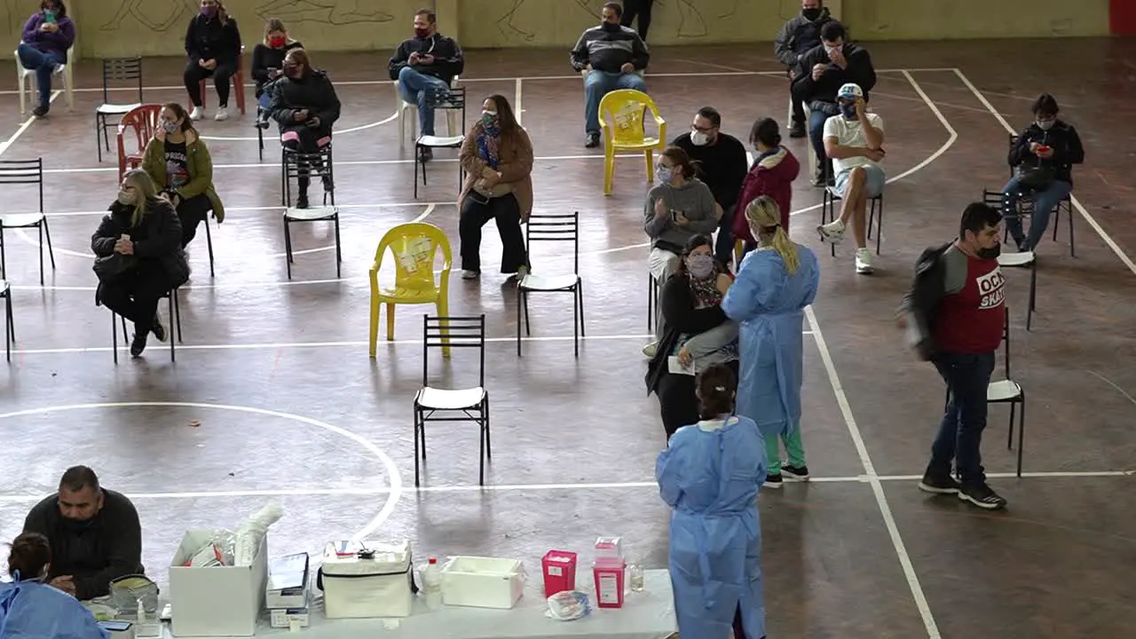 Establishing shot of people waiting their turn as healthcare workers apply COVID-19 vaccines