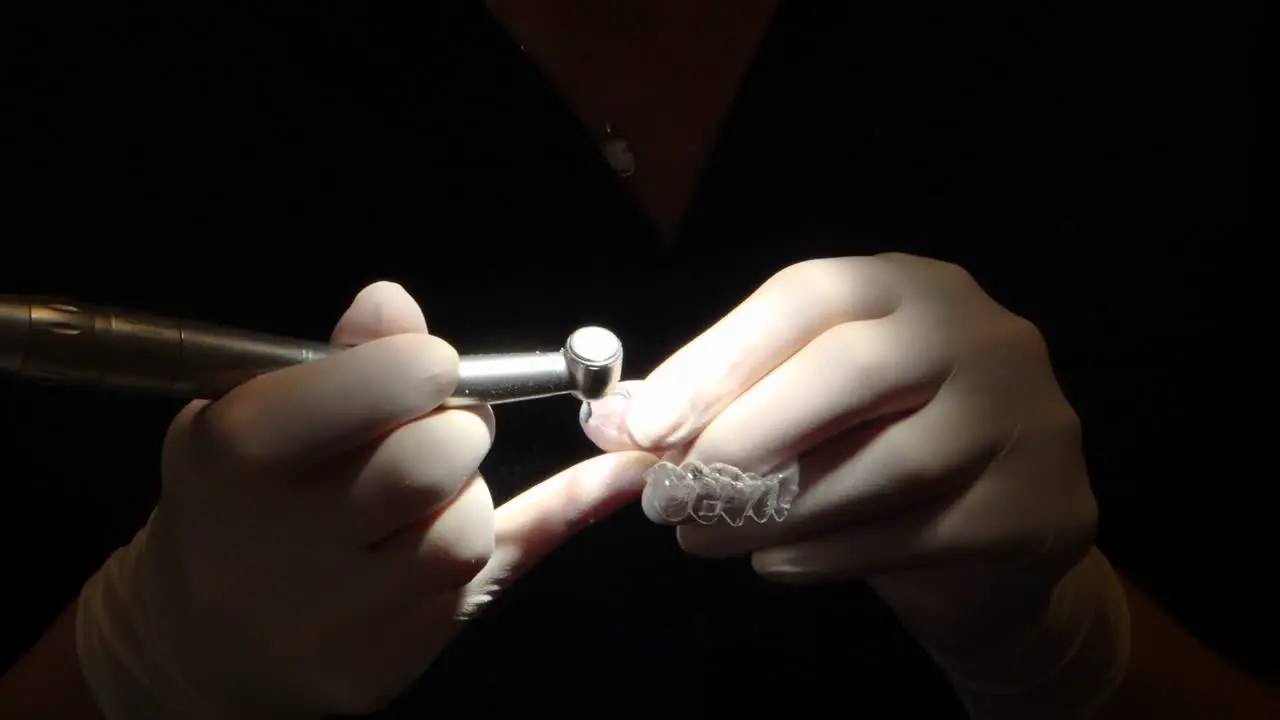 close-up view of orthodontist costuming an invisalign aligner in dark setting with focus light