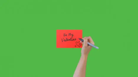 Woman Writing Be My Valentine on Paper with Green Screen