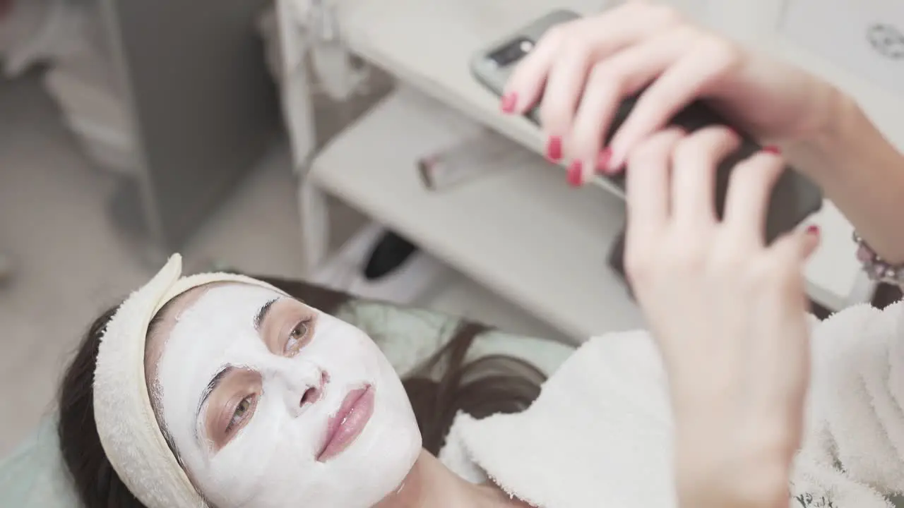 Girl smiling and taking photos of herself with a face mask applied