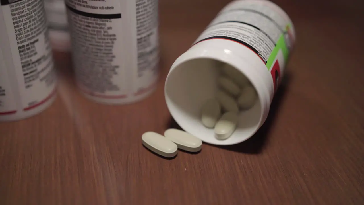 Man picks up white vitamin tablets or pills from the table