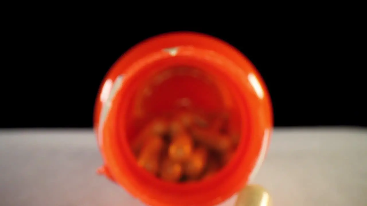 moving past cap slowly pushing into an orange supplement pill bottle