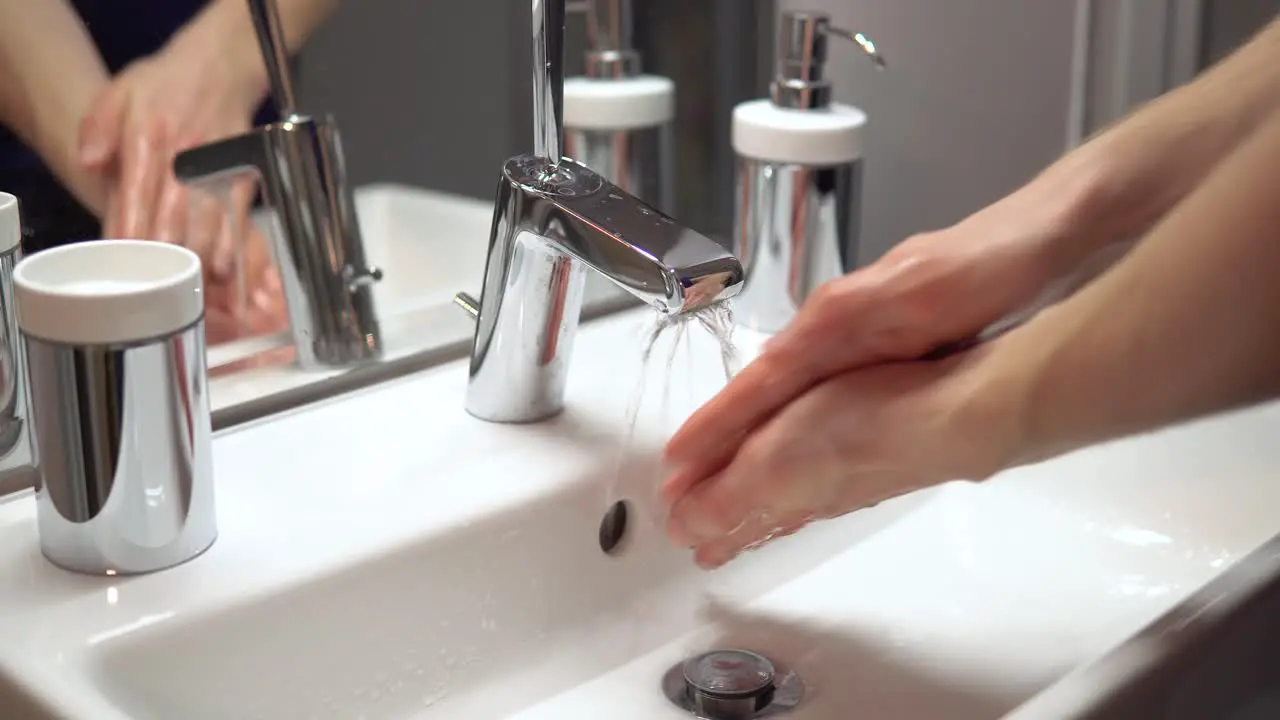 Close-up of person washing hands in clean bathroom