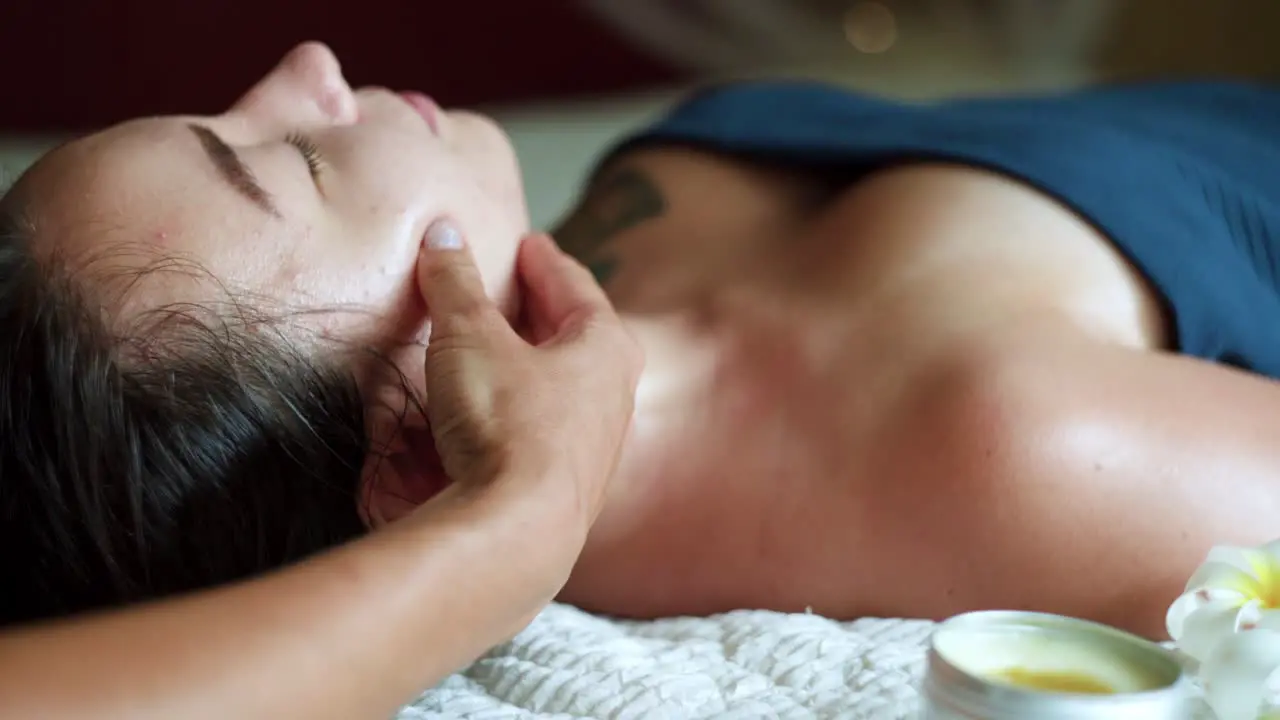 Pretty brunette receiving face massage with oil at home