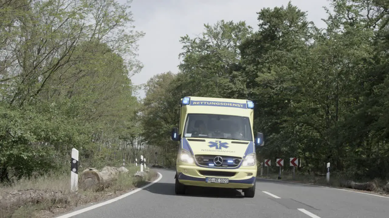 Front view on ambulance driving on forest road slow motion dolly shot