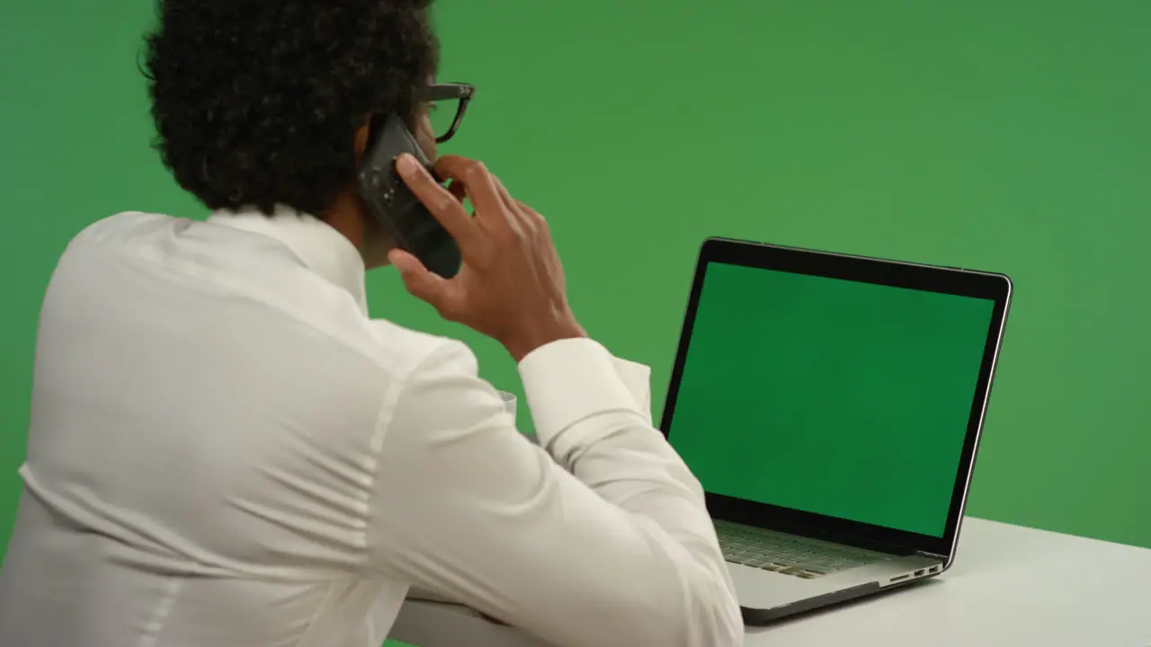 Businessman Answers Phone While Using Laptop