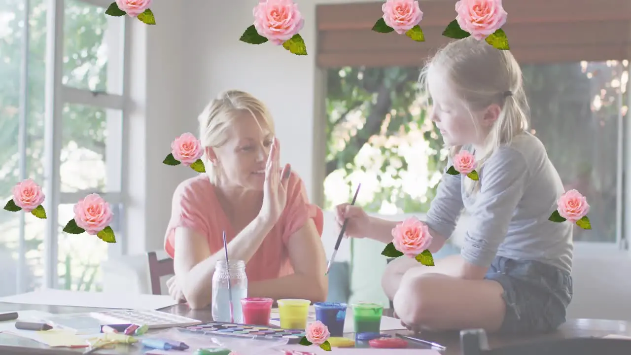 Animation of roses over happy caucasian mother and daughter painting together