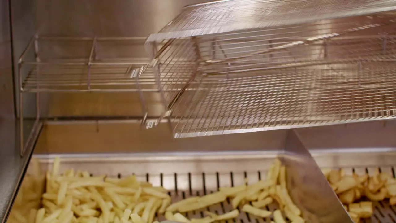 French fries taken out of oil and placed on grate in fast food kitchen