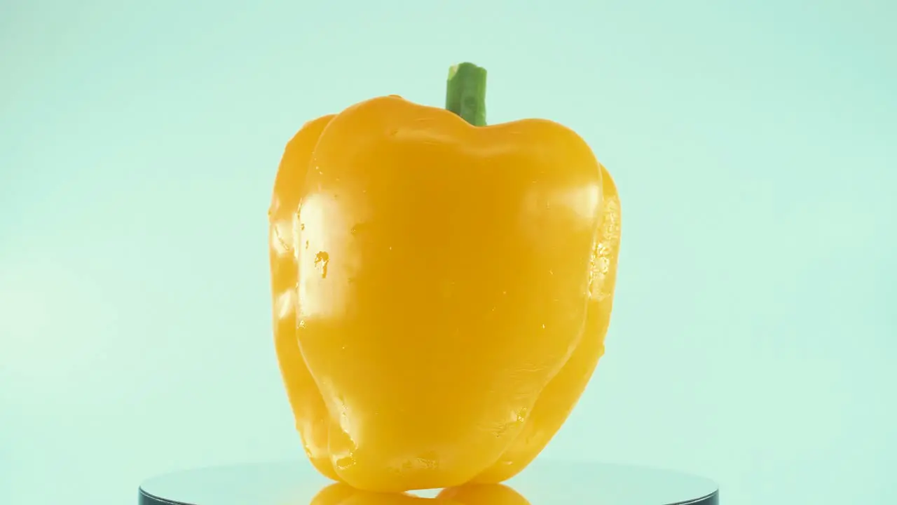 A close up shot of a sweet yellow pepper on a reflecting rotating stand 360 slow motion 4k