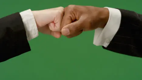 CU Colleagues in suits fist bump on green screen