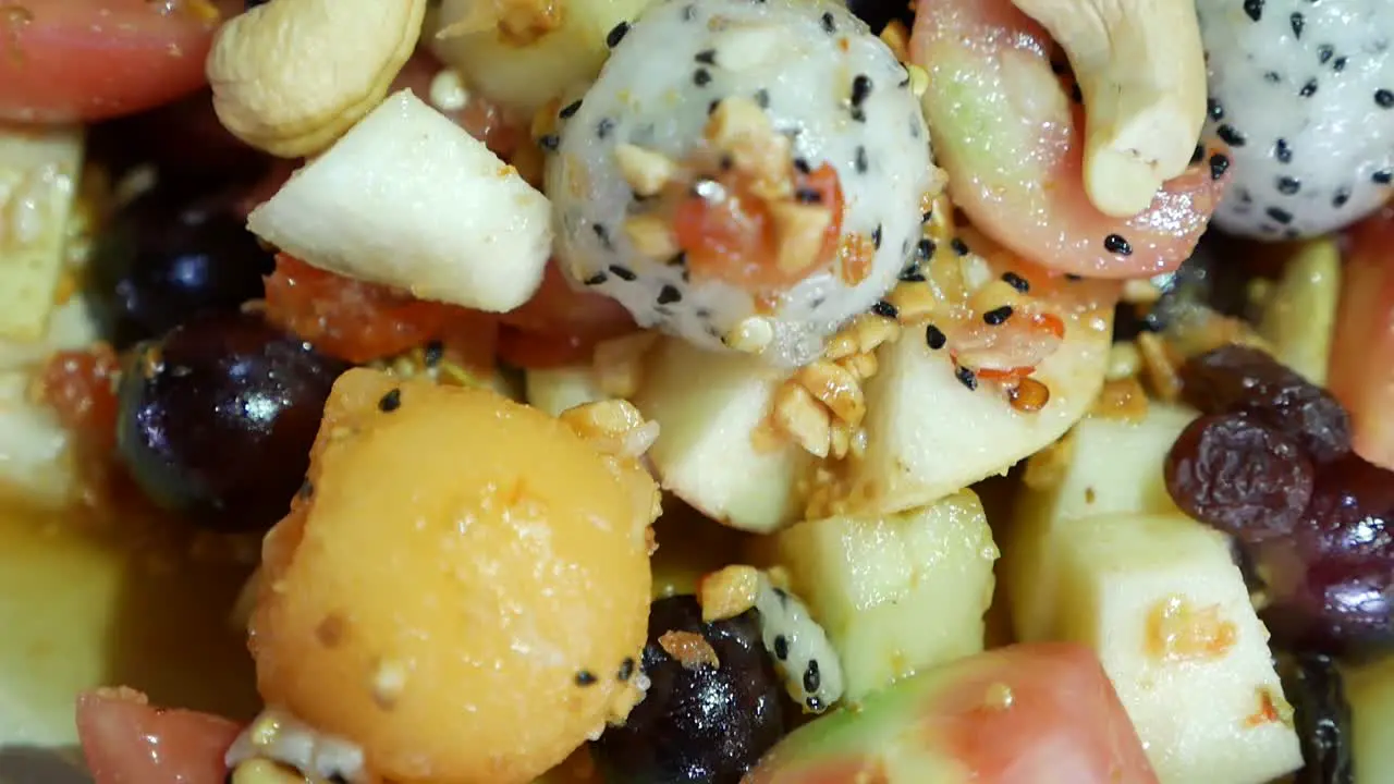 Close Up Footage of Thai Style Mix Exotic Fruits Somtum with Sweet and Salty Dressing Included Dragon Fruit Cashew Nut Grape Guava Melon and Tomato