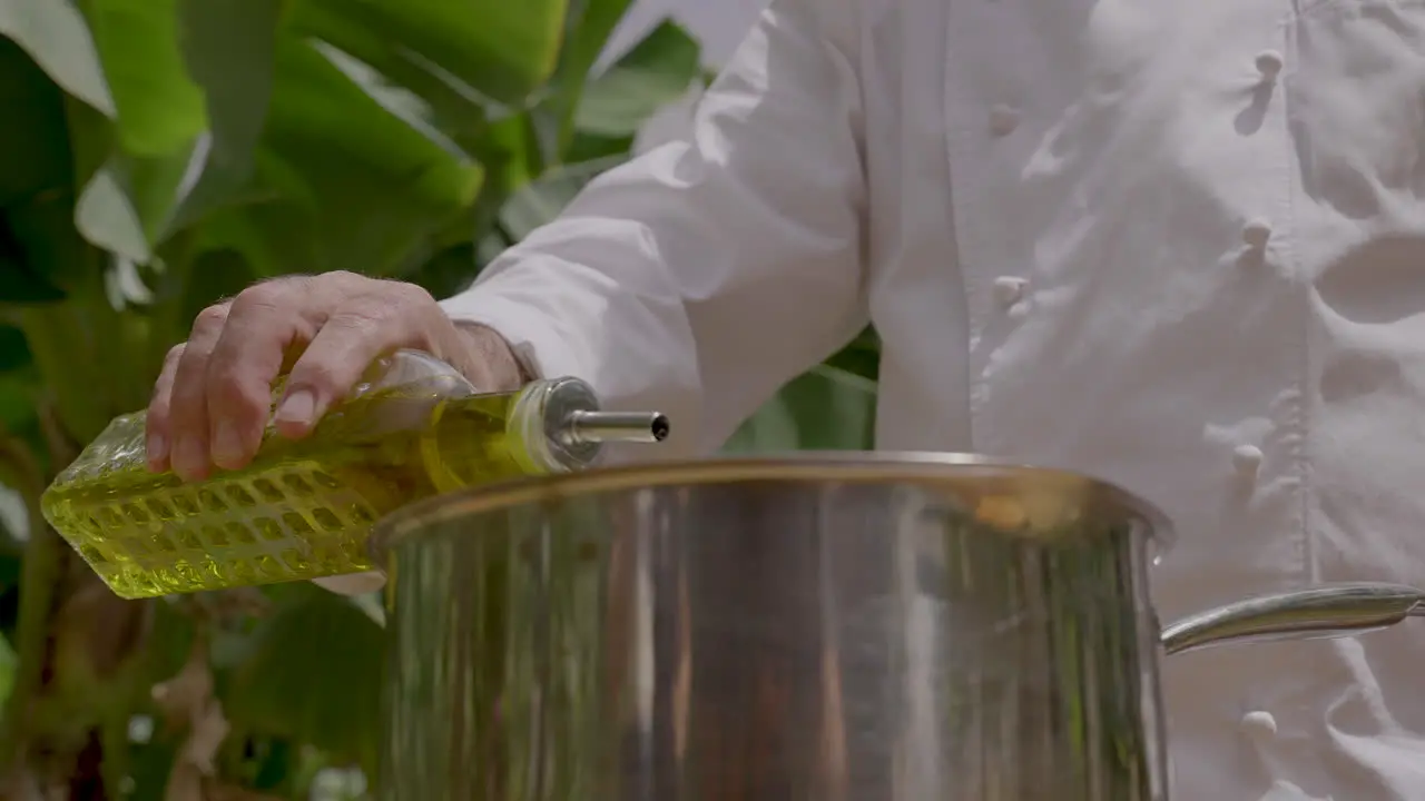 Chef pouring extra virgin olive oil on a metal pan