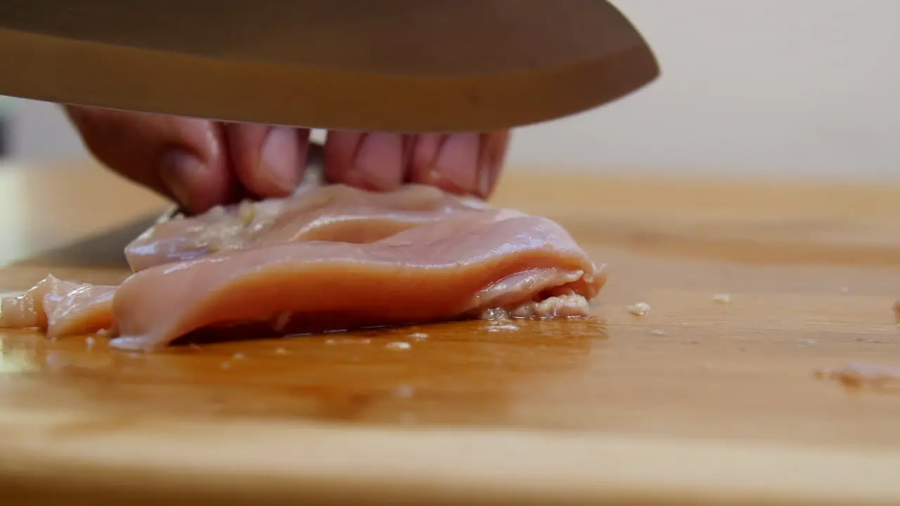 Hand cuts raw chicken into strips