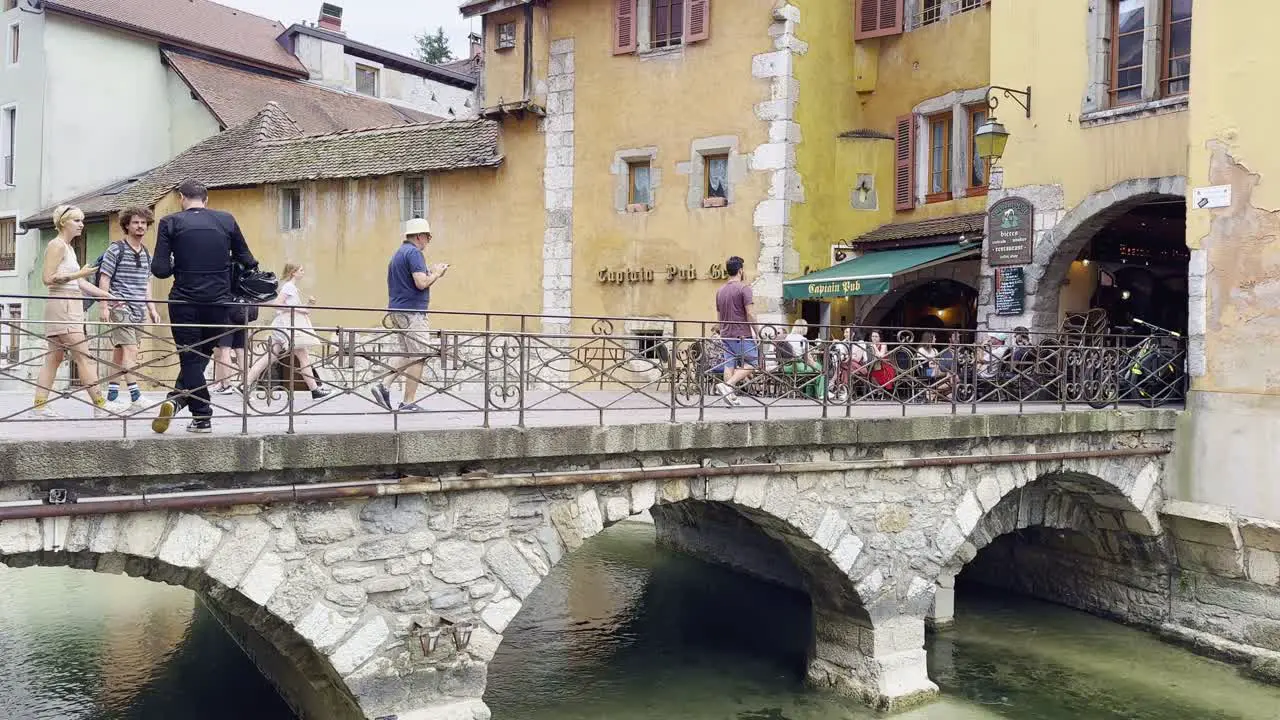 Tourists pedestrians on a stone bridge in Annecy with beautiful architecture