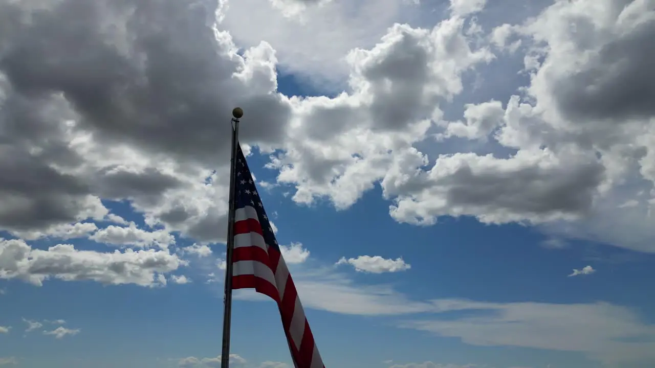 American flag USA blowing waving in the wind on beautiful sunny summer day with clouds and blue skies overlooking mountains in 4K 60fps