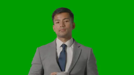 Studio Shot Of Businessman In Suit Holding Cup Of Hot Drink Against Green Screen 