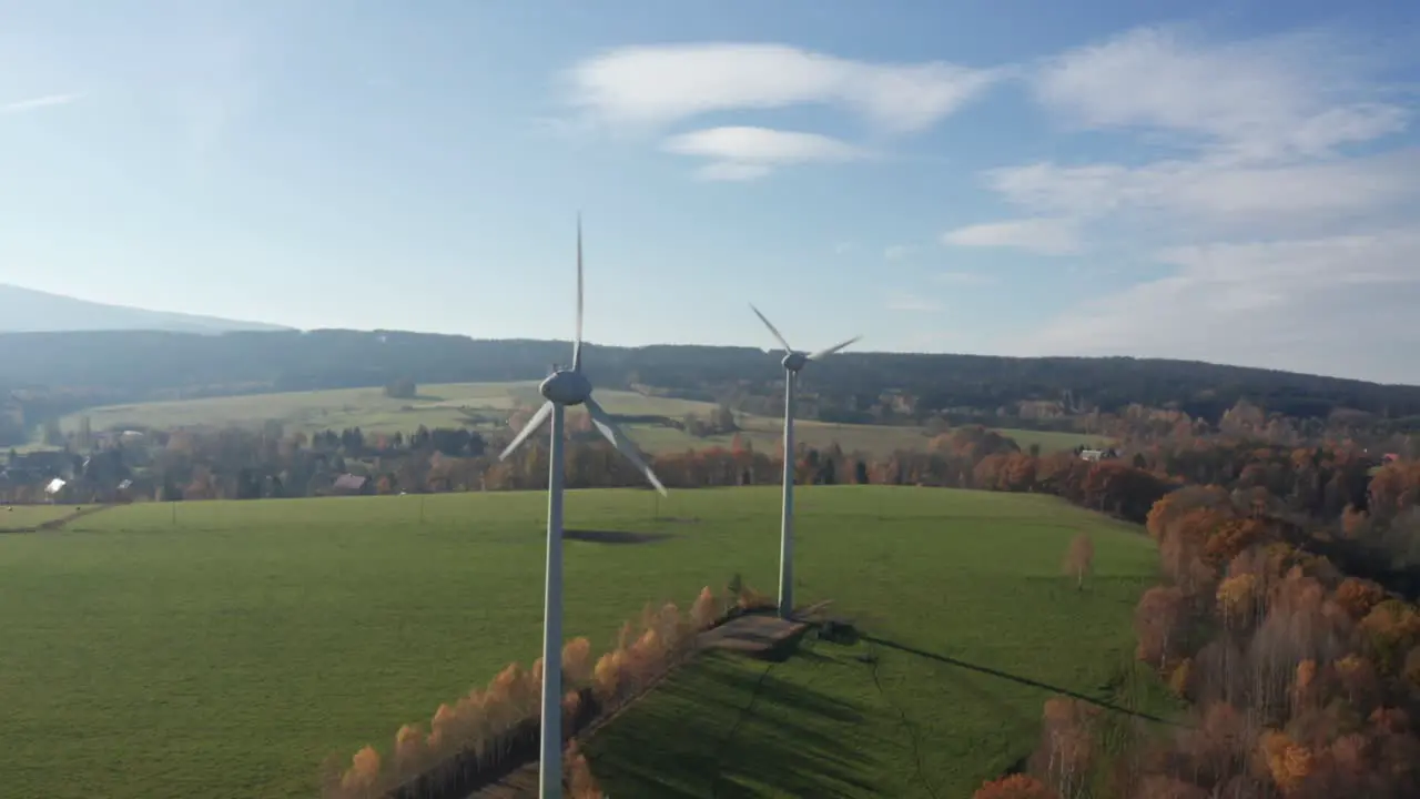 Wind power stations on sunny day near village surrounded by meadow