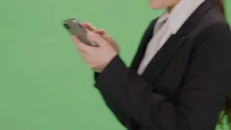 CU Businesswoman texting while walking on green screen