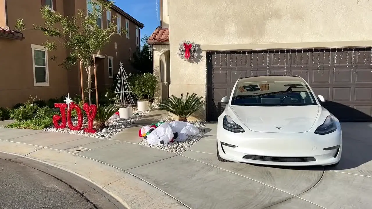 Electric Tesla car parked outside sunny home celebrating festive Christmas holiday