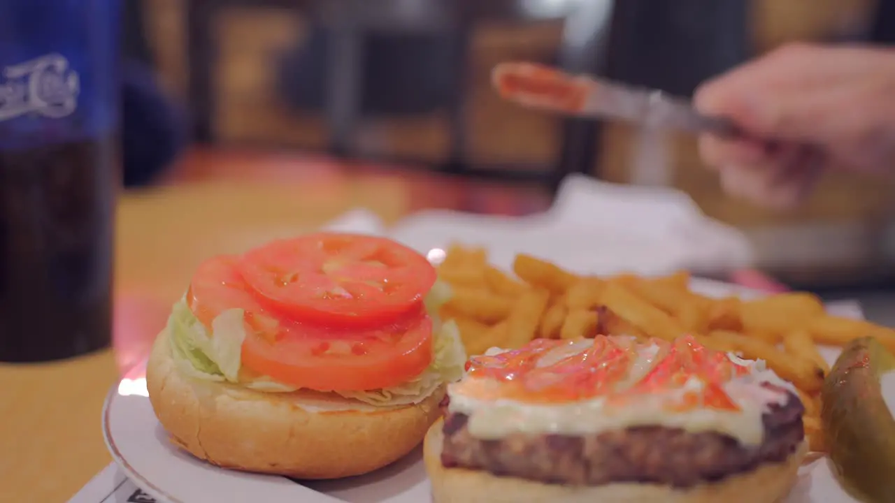 Customer Spreading Dressing On Burger Patty In A Plate Of Burger Meal At American Diner