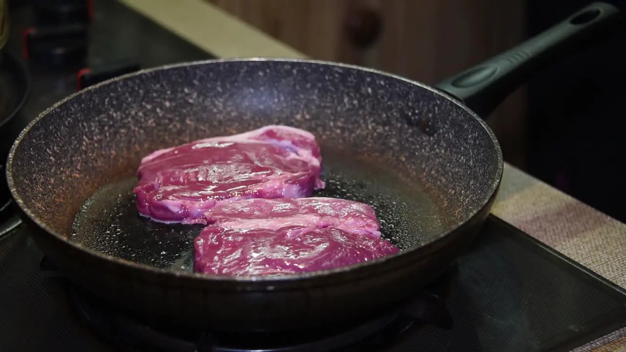 Raw steaks going into a frying pan