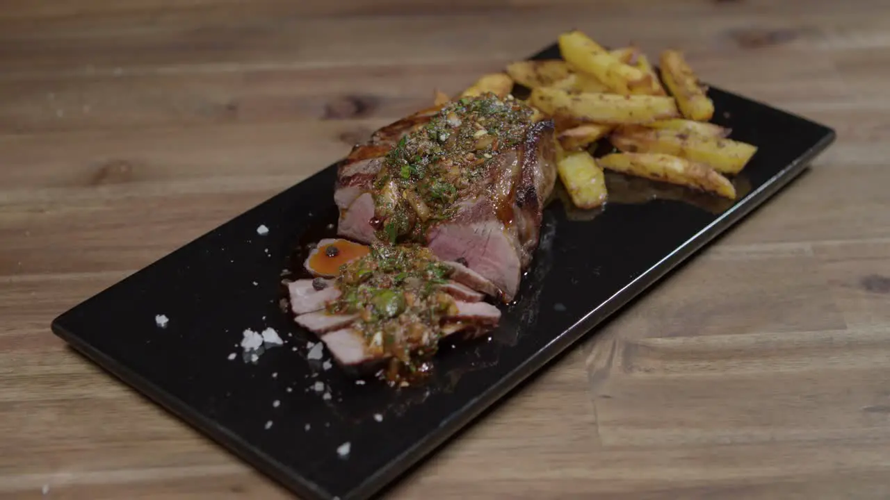 Slices of meat with chimichurri and cafe en paris butter on kitchen board accompanied with french fries argentinian food