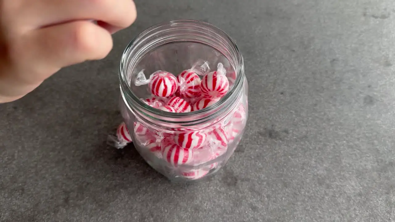 Kid hand takes candy out of a glass jar and then takes entire jar