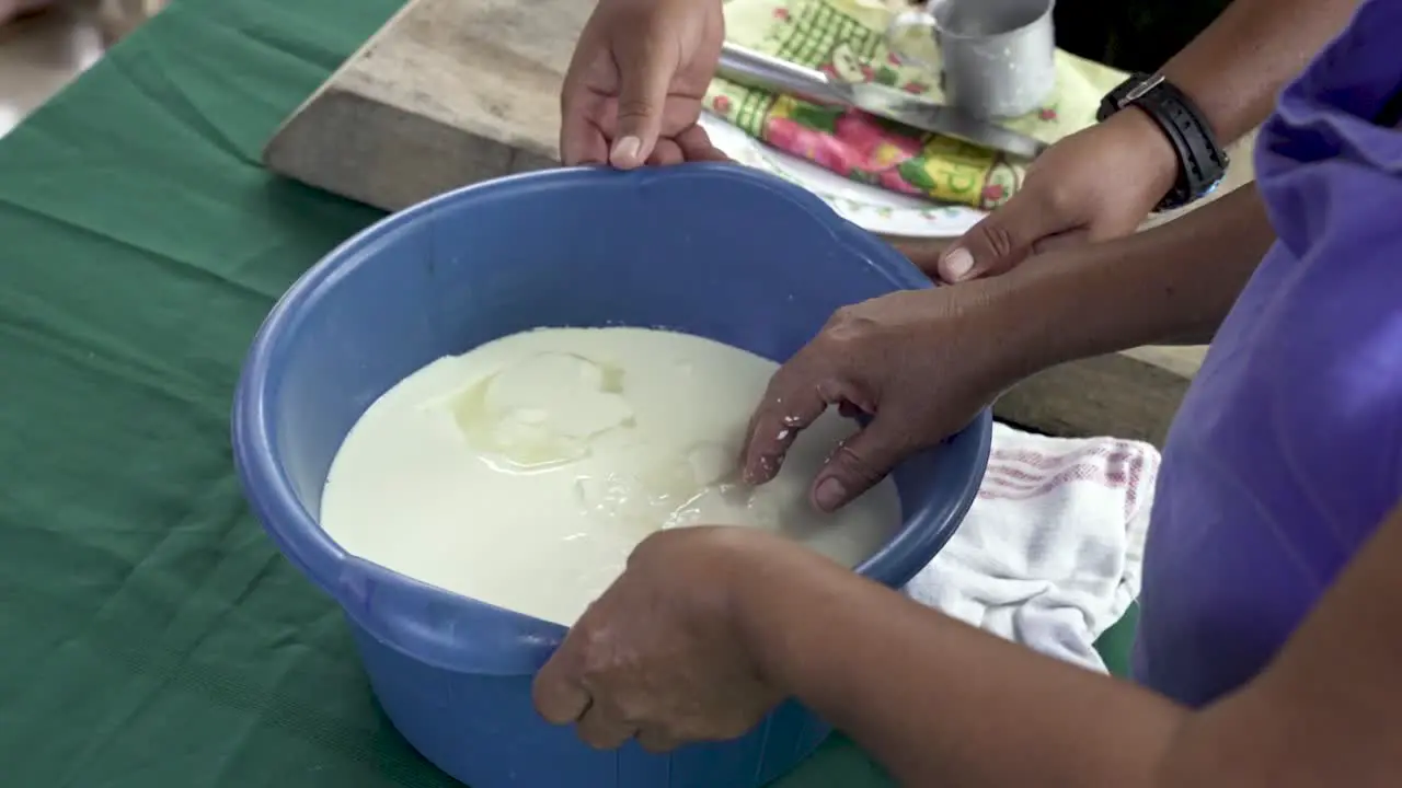 Cheese Curds in blue bucket with Indigenous woman from Costa Rica pressing the pail ball Close up handheld shot