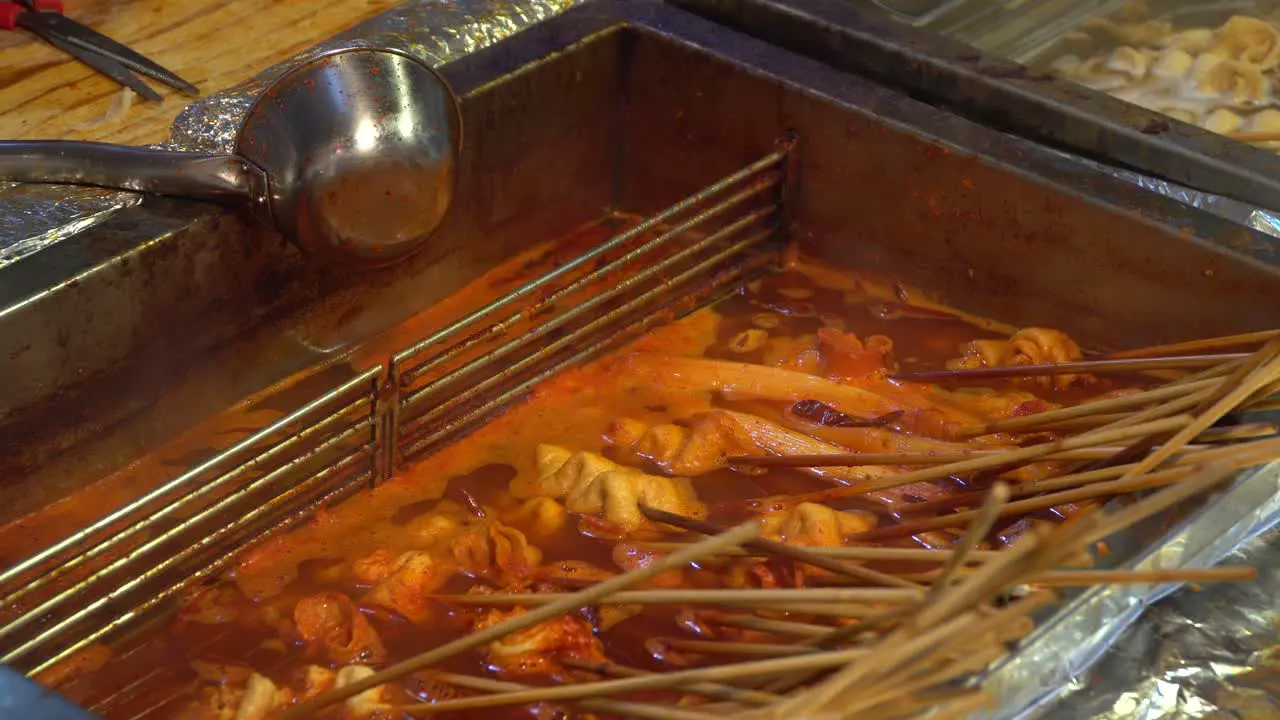 Hand taking korean spicy oden from the pot  street food