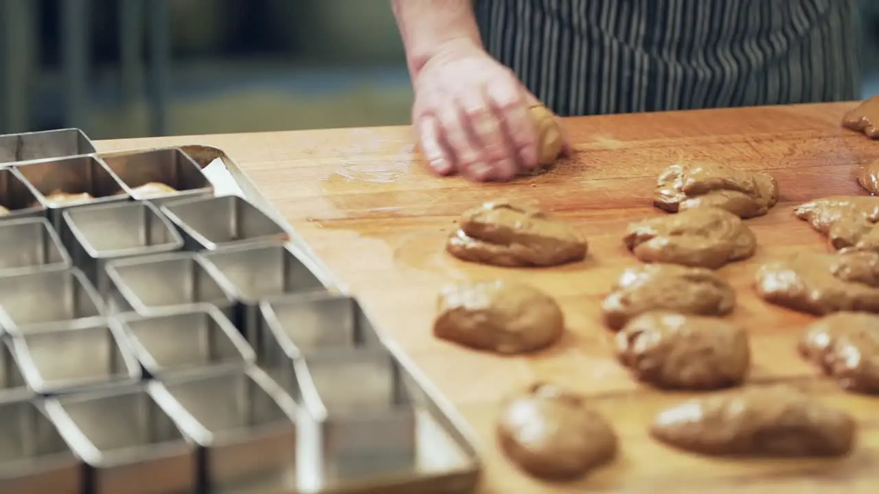 the baker kneads the dough into buns and puts them into shape before baking