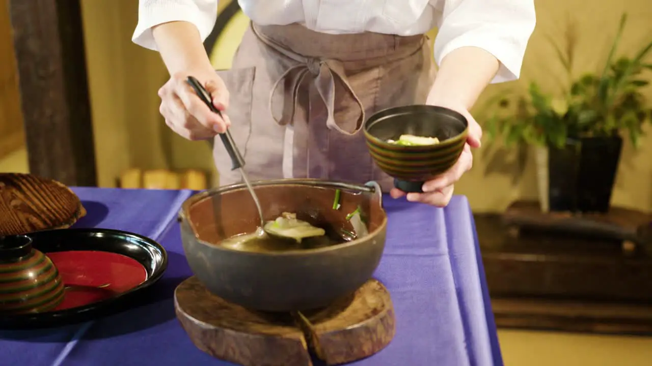 Woman in traditional Japanese clothes serving miso soup