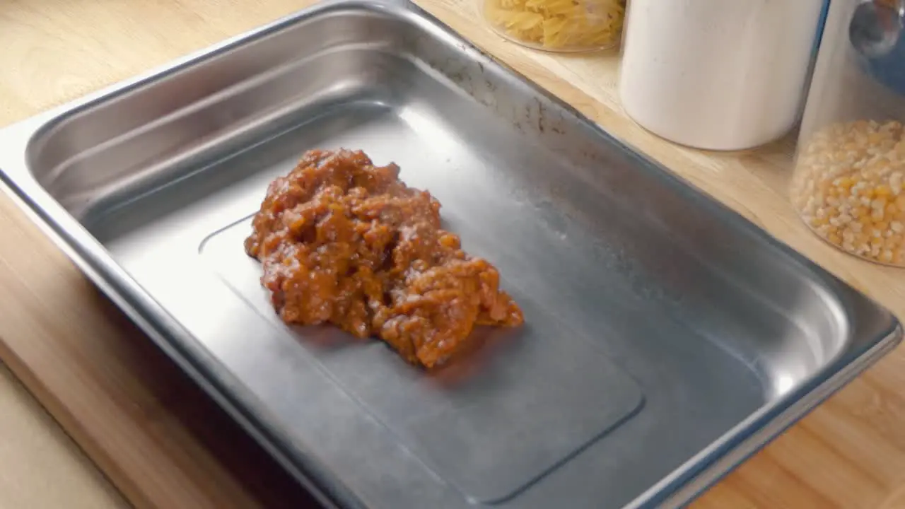 Medium Shot of Adding Tomato Sauce to a Baking Tray for Making Lasagne