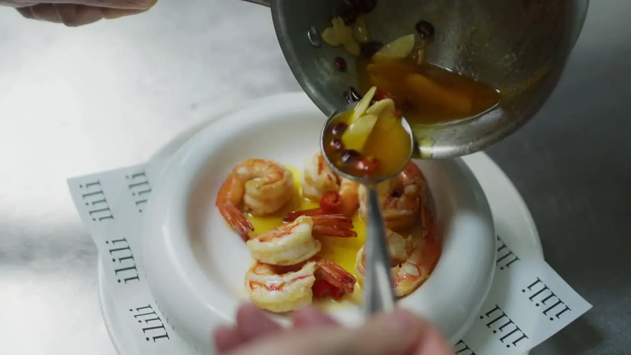 Chef pouring olive oil over Mediterranean fresh seafood shrimp soup traditional healthy dish