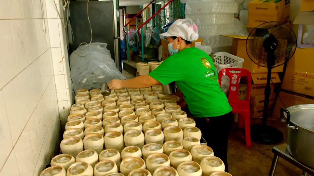 Backroom of coco jelly store with woman preparing the traditional street food pouring coconut water jelly into coconut shell