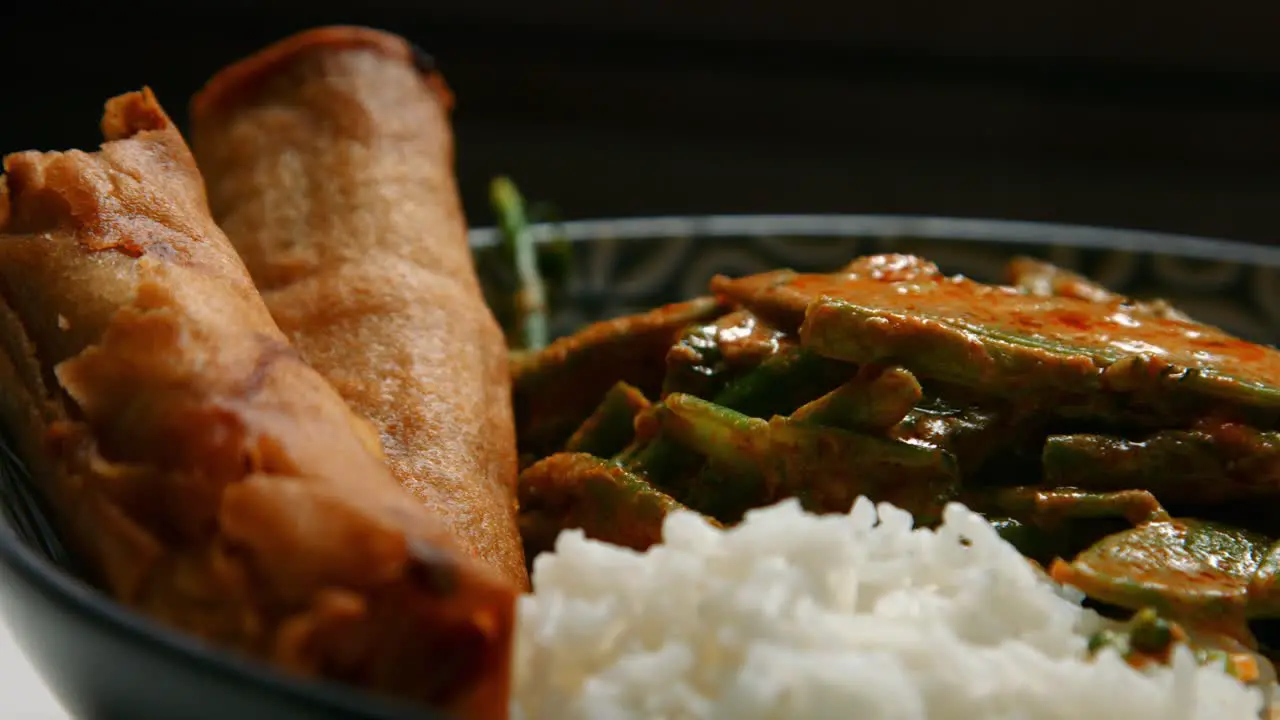 Slow Pan of Vegan Thai Red Curry with Rice and Spring Rolls