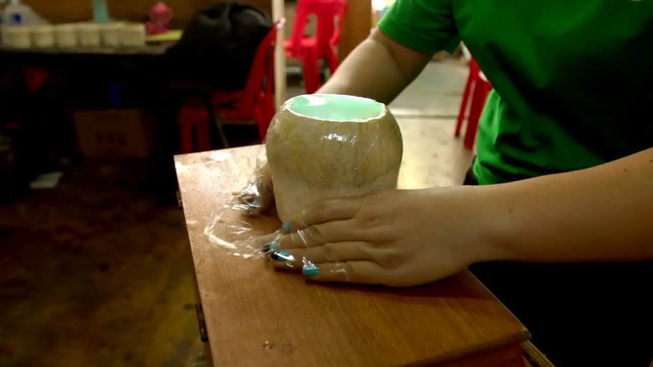 Unrecognizable woman wrapping coconut filled with coco jelly traditional thai street food made with coconut pulp and water jelly